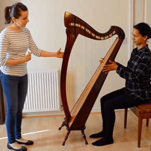 Zuzanna teaching a student how to play harp
